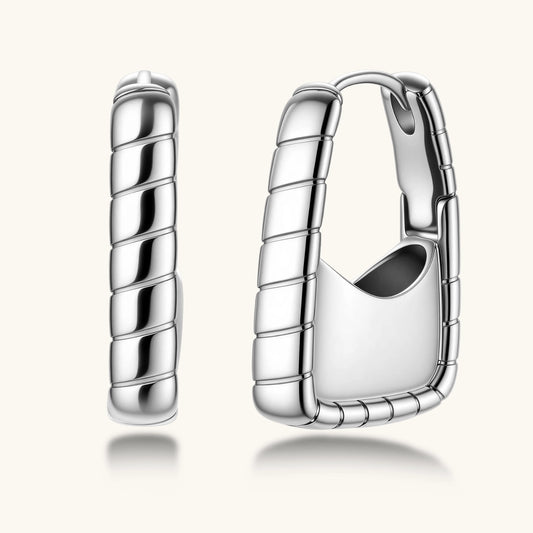 Close-up of platinum-plated sterling silver hoop earrings with horizontal textured grooves on white background.