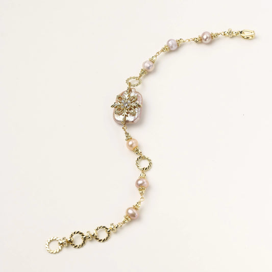 Gold-plated bracelet with pink baroque pearl centerpiece, floral connector, and freshwater pearls