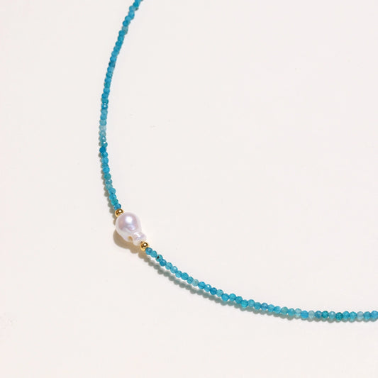 Delicate gold vermeil necklace with teal apatite beads and freshwater pearl on white background.