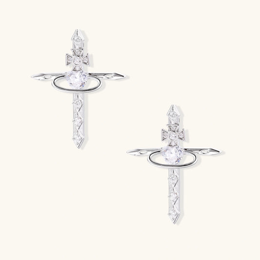 White gold plated cross earrings with orbital ring & zirconia stones on cream background