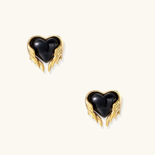 Glossy black heart-shaped studs with gold wing accents on cream background, gothic romantic style earrings