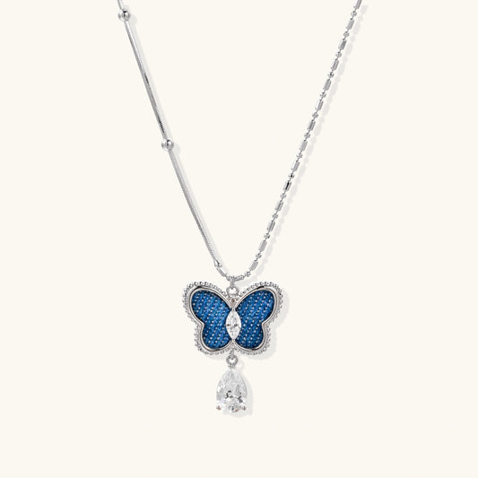 Silver-toned butterfly pendant with blue denim fabric inlay and teardrop crystal on dual-chain necklace