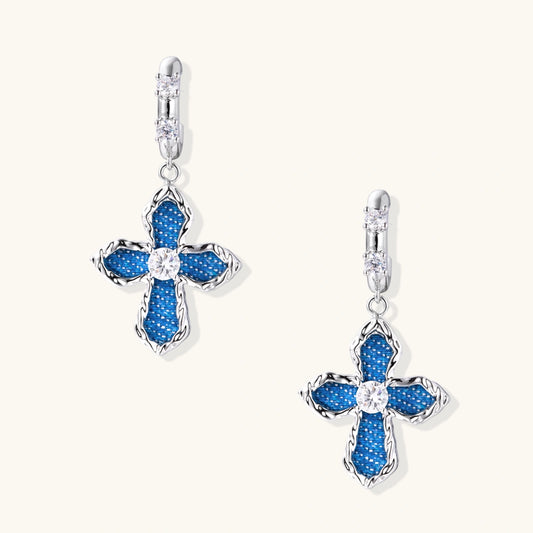 Silver hoops with denim-inlaid cross charms and clear crystals on beige background