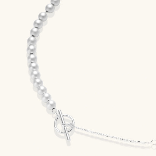 Long sterling silver beaded necklace with graduated sphere design, toggle clasp, and delicate chain extension on white background