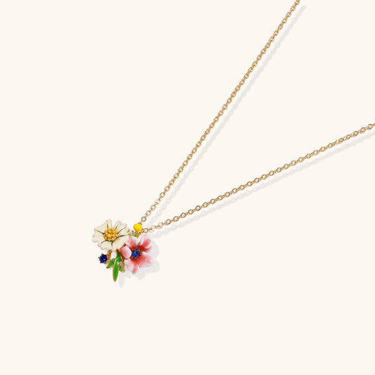 Enamel floral pendant necklace with white daisy, pink flower, yellow and blue accents on gold chain against cream background.