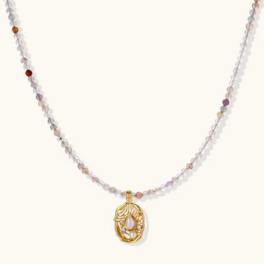 Delicate gold-plated necklace with mixed gemstone beads and ornate oval pendant on white background