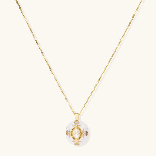 Gold-plated necklace with circular white enamel pendant featuring central zirconia stone and ornate decorative details
