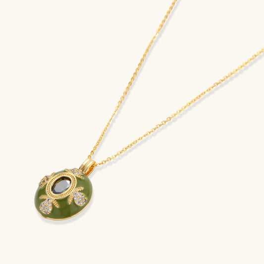 Gold-plated pendant necklace with green enamel background and oval olive cubic zirconia center stone with crystal accents.