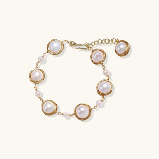Gold wire-wrapped freshwater pearl bracelet with alternating pearl sizes on cream background, adjustable length