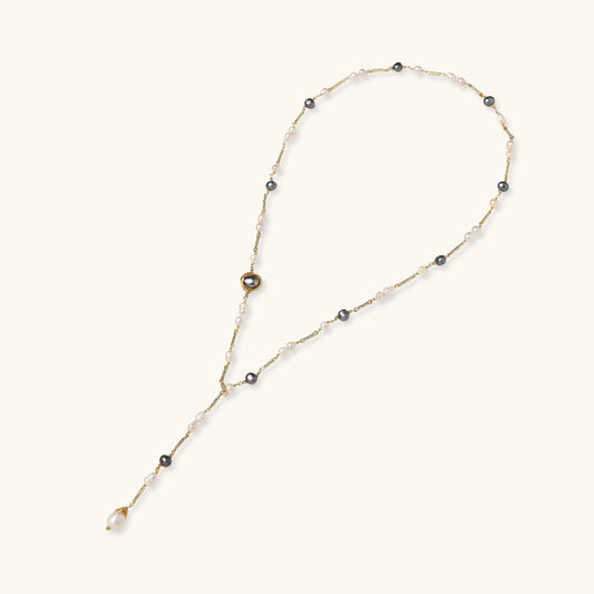 Y-shaped gold-plated necklace with white and gray freshwater pearls on cream background, showing adjustable drop design.