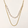 Layered gold chain necklace with organic baroque freshwater pearls and adjustable length on cream background