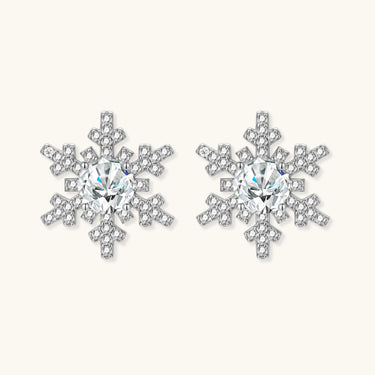 Sterling silver snowflake stud earrings with brilliant moissanite centers and intricate geometric patterns on cream background