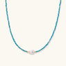 Delicate gold vermeil necklace with teal apatite beads and freshwater pearl on white background.