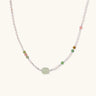 Delicate pearl necklace with pale green serpentine jade centerpiece and colorful agate beads on cream background