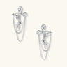 Sculptural white gold bow earrings with cascading chain details on neutral background