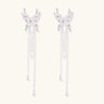 Elegant chandelier earrings with phoenix wing design, white pearls, and cascading silver chains on cream background