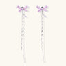 Long drop earrings with translucent lavender enamel dragonfly wings and white gold plated segmented bodies on white background