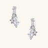 White gold-plated huggie earrings with geometric emerald-cut zirconia clusters in starburst formation on beige background