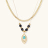 Layered gold necklace with turquoise evil eye pendant and black quartz beads on cream background
