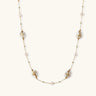 Long gold chain necklace with baroque pearls wrapped in leaf designs and small freshwater pearls spaced along the strand