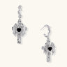 Silver drop earrings with twisted hoops and angel wings embracing black heart locket on white background.